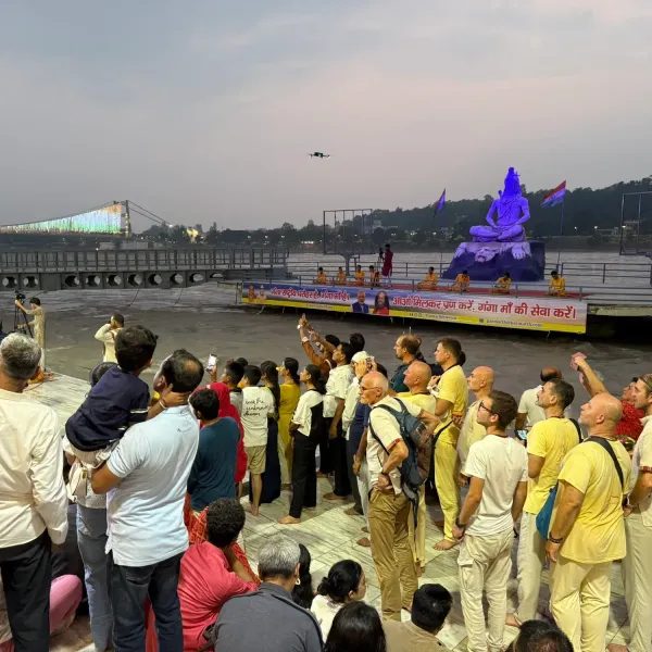 The group standing on the Parmarth Niketan ghat at dusk, facing the Shiva statue on the Ganges before the evening Aarti