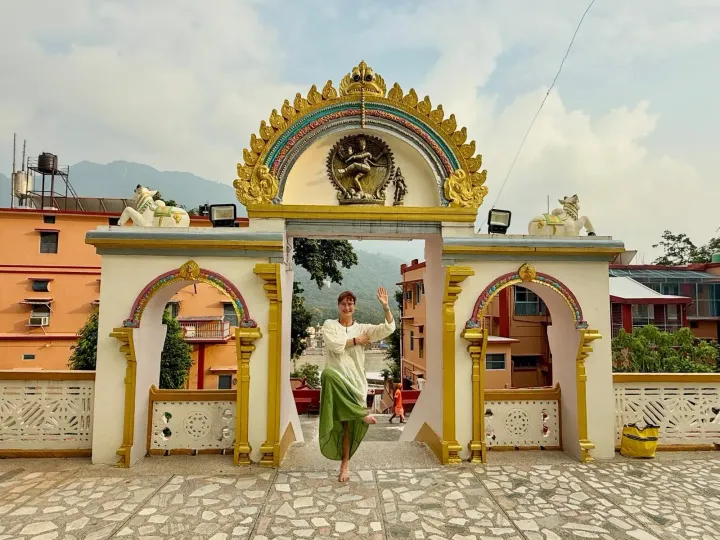 Woman in tree pose in front of the ornate gateway of Sivananda Ashram in Rishikesh