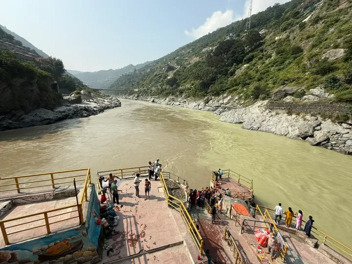 The confluence at Devprayag where the grey Bhagirathi and the green Alaknanda meet, with pilgrims bathing at the ghat