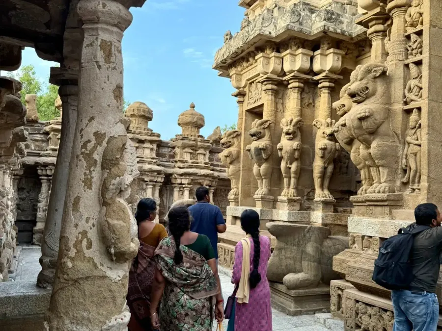 Visitors walking among carved stone pillars and lion sculptures of the Kailasanathar temple in Kanchipuram