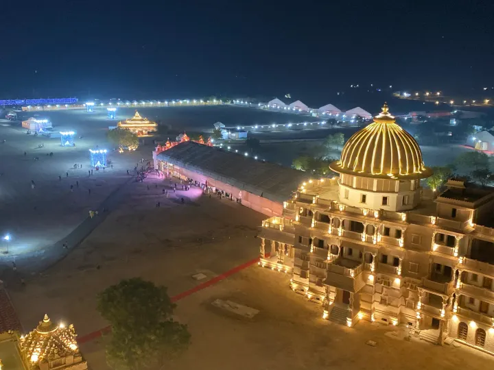Om Ashram at Jadan lit up at night, seen from above with its golden dome