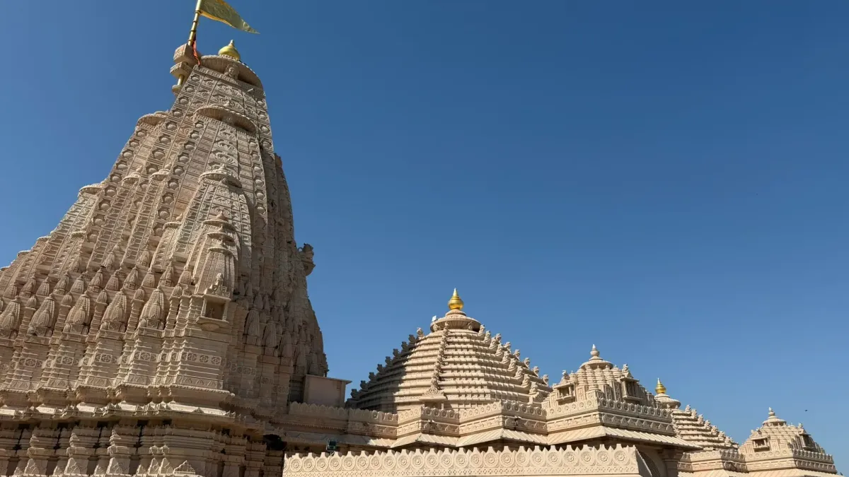 The carved sandstone spire of the temple at Om Ashram against a clear blue sky