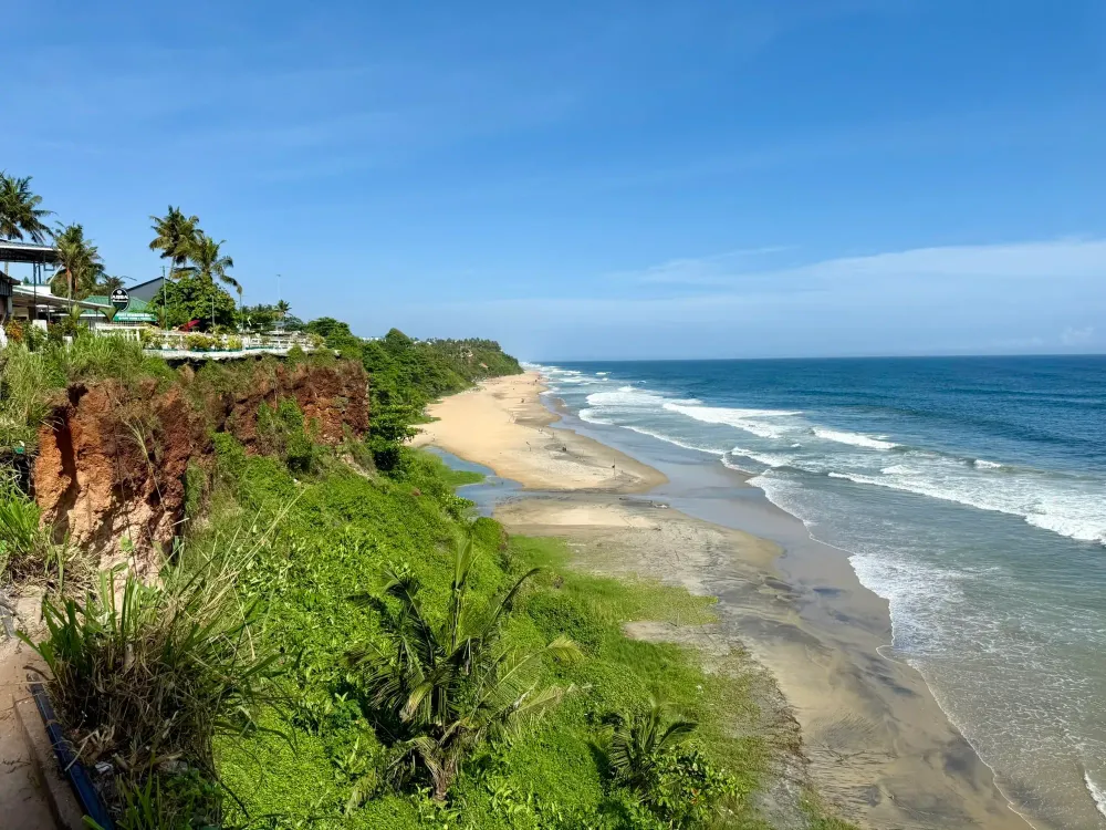Red cliffs, palms and a long sandy beach on the Arabian Sea at Varkala, Kerala