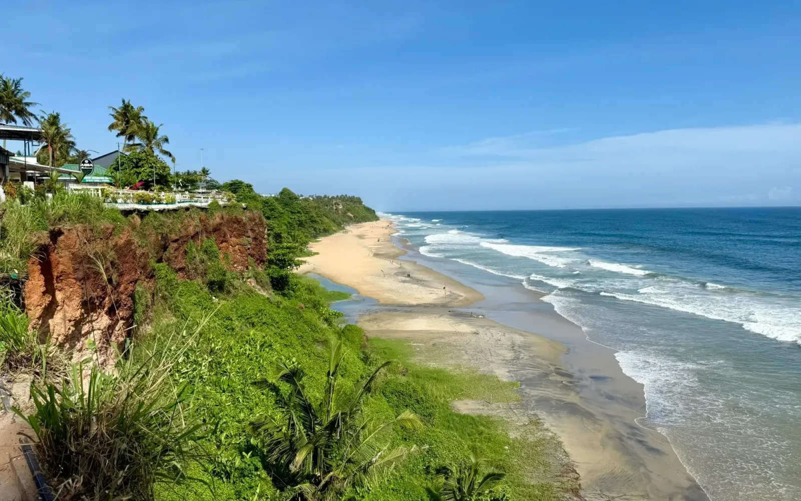 Red cliffs, palms and a long sandy beach on the Arabian Sea at Varkala, Kerala