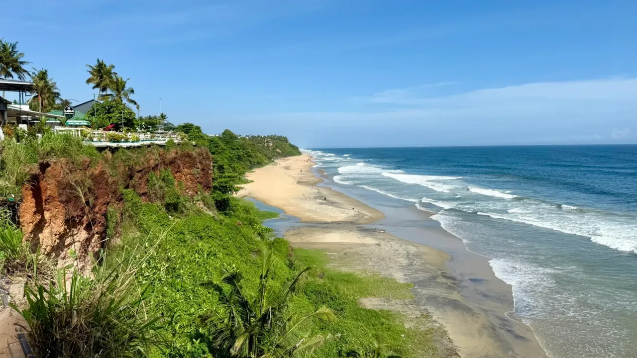Red cliffs, palms and a long sandy beach on the Arabian Sea at Varkala, Kerala