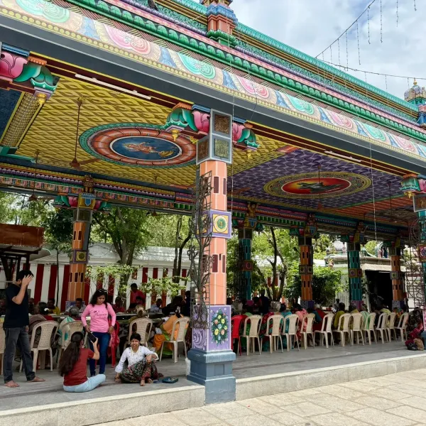 Brightly painted temple pavilion with pilgrims gathered beneath it, Tamil Nadu
