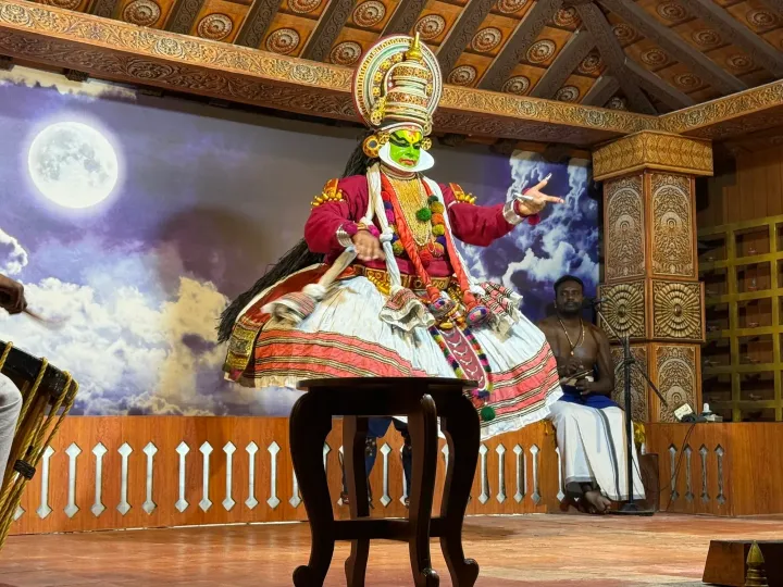 A Kathakali dancer in full costume and green make-up performing on stage in Kerala