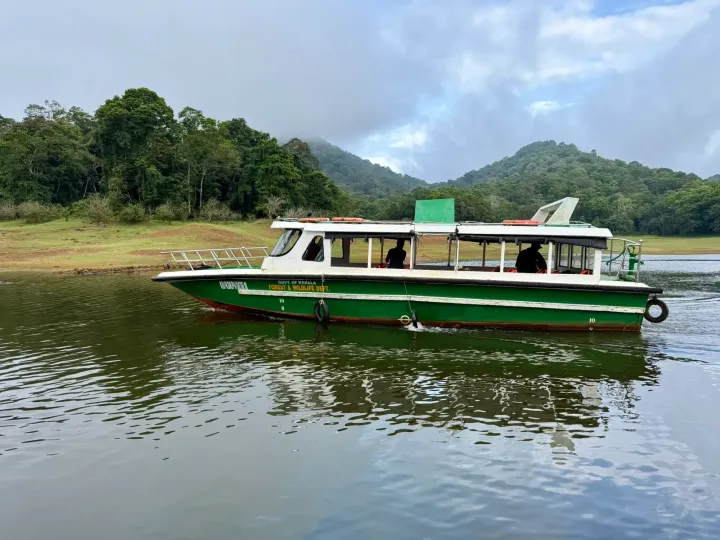 A forest department boat on Periyar Lake with tropical forest behind, Thekkady